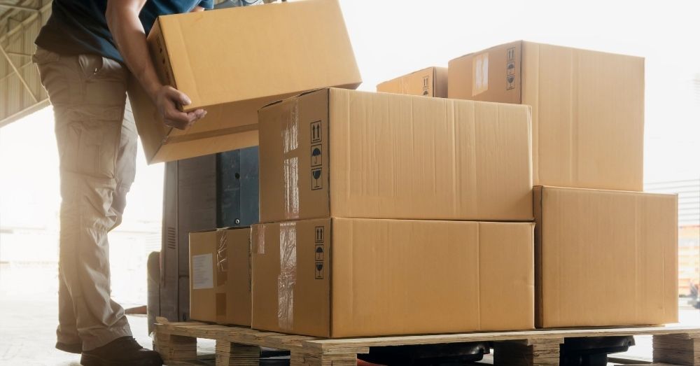 A man organizing the boxes on a pallet.