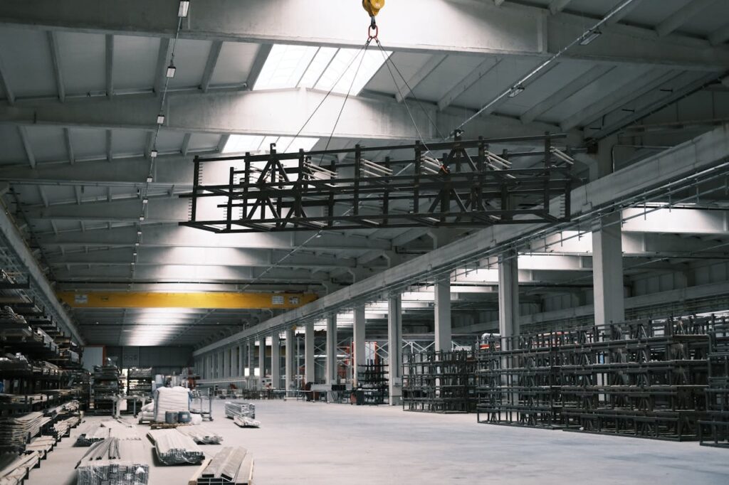 An overhead crane lifts a steel structure in a factory.