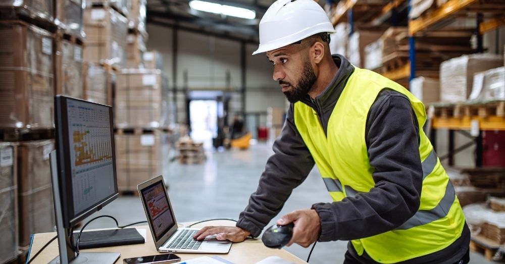 Warehouse worker uses laptop to track inventory (fcfs meaning).